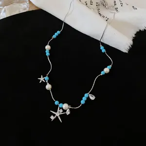 Detail einer Perlenkette mit Zirkonia-Seestern auf elegantem schwarzem Hintergrund.
