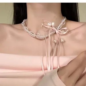 Close-up of balletcore ribbon bow necklace with beaded chains and lily-of-the-valley