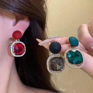 Close-up of three colors of matte spray paint earrings with vibrant crystal halos