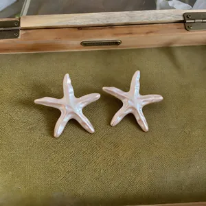 Vue détaillée de breloques étoile de mer rose perlé sur un fond vintage vert olive
