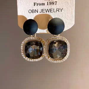 Macro detail of elegant black matte stud earrings with crystal halo and grey gemstone