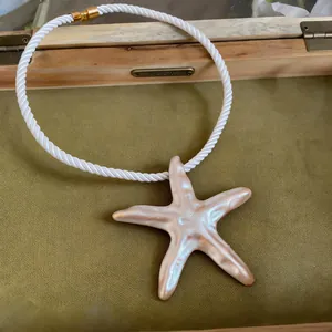 Vue détaillée d'un collier pendentif étoile de mer nacré avec cordon blanc torsadé