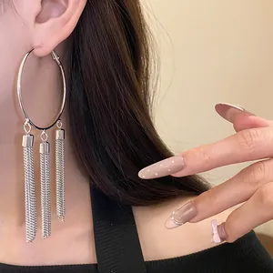 Close-up of silver hoop earrings with long chain tassels for a retro look