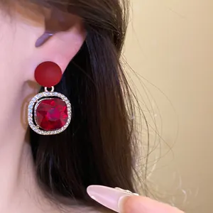 Detail of red gemstone drop earrings with sparkling crystal-encrusted gold frame