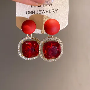 Macro view of exquisite red crystal earrings featuring a matte finish and rhinestones.