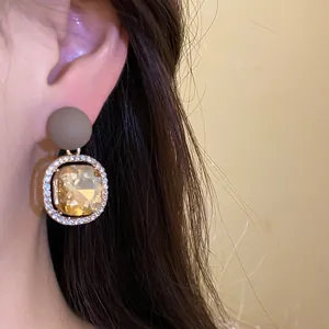 Detailed macro view of elegant amber crystal earring with matte stud and diamond accents