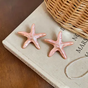 Vue détaillée de deux accessoires étoiles de mer rose iridescent sur une page de livre.