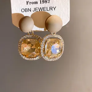 Detail of elegant champagne stone earrings with matte beige stud and rhinestones.