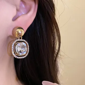 Detailed macro view of a gold-toned earring featuring a large crystal and rhinestone halo.