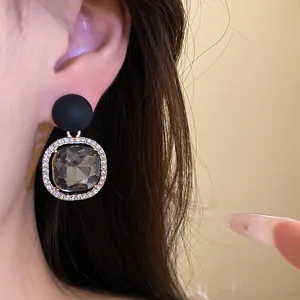 Close-up detail of silver needle earrings with matte black finish and rhinestone accents