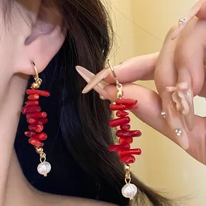 Close-up detail of retro red resin and pearl tassel drop earrings worn on an Asian model