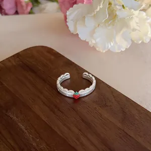 Dettaglio di un anello a fragola in argento con bordo smerlato su superficie di legno