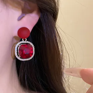 Close-up of elegant red gemstone earrings with silver needle and diamond accents