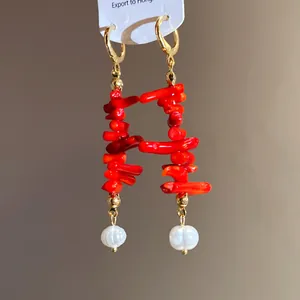 Detailed macro view of retro red resin segments and pearl tassel earrings with gold finish