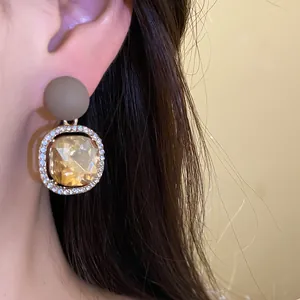 Detail showing a stylish silver needle stud earring with matte finish and sparkling crystals