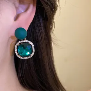 Detailed close-up of a green matte stud earring with a shimmering emerald gem.