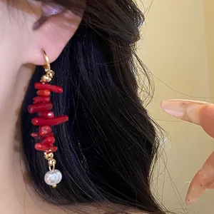 Close-up of retro red resin tassel earring with a white pearl drop worn on the ear