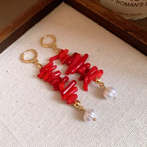 Close-up detail of vintage hoop earrings with red resin coral branches and white pearls.