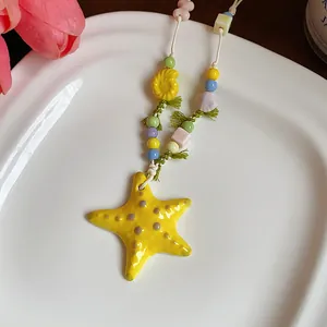 Close-up detail showing a vibrant yellow ceramic starfish pendant with colorful beads.