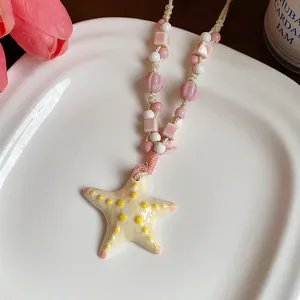 Detailed view of the ceramic starfish pendant on a pink and white beaded rope necklace