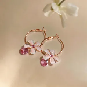 Close-up of elegant rose gold hoop earrings with pink resin flower and crystal drop
