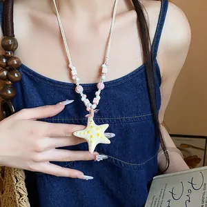 Detailed view of a dopamine-style beaded necklace with a ceramic starfish pendant on a model.