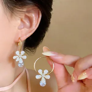 Close-up detail of a delicate resin flower and zircon drop on a gold-tone hoop earring