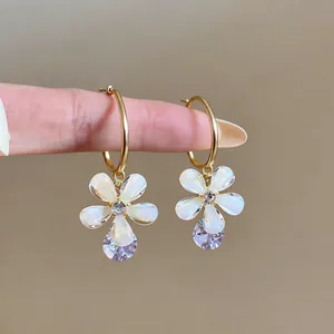 Detailed view of sparkling zircon drops and resin flower petals on elegant golden hoop earrings