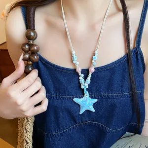 Detailed close-up of a handmade ceramic starfish pendant with colorful beads on a white rope necklace