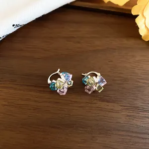 Detailansicht eleganter goldener Huggie-Ohrringe mit farbenfrohen Kristallperlen-Clustern