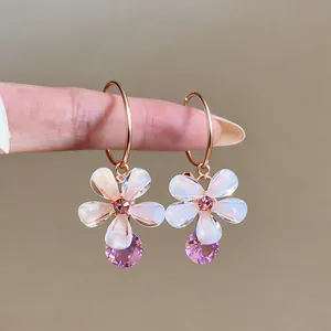 Close-up of French-style resin flower earrings with purple crystal drop details.