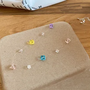 Detailansicht bunter quadratischer Kristallperlen an einer dünnen transparenten Halskette.