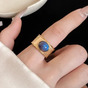 Gros plan d'une bague dorée texturée ornée d'une pierre ovale bleue iridescente.