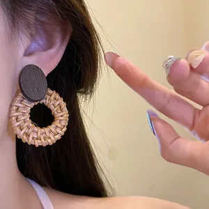 Close-up of ethnic retro earring featuring a dark wood stud and woven rattan circle