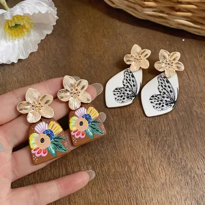 Eleganti orecchini a perno con fiori dorati e motivi artistici di farfalle e fiori