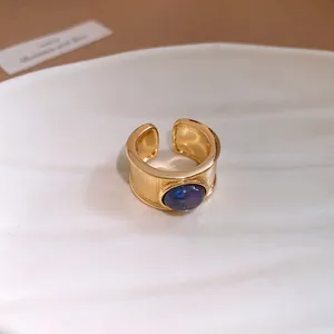 Gros plan d'une bague ouverte dorée vintage ornée d'une pierre ronde bleu foncé