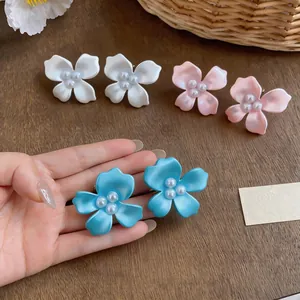Close-up view of sweet floral stud earrings featuring pearls in vibrant blue, pink and white.