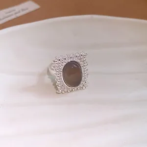 Vue détaillée d'une bague en argent avec une pierre ovale grise et un cadre carré texturé