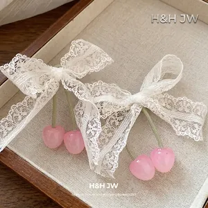 Elegant white lace bow hair clips featuring pink cherry pendants set in a beige jewelry tray