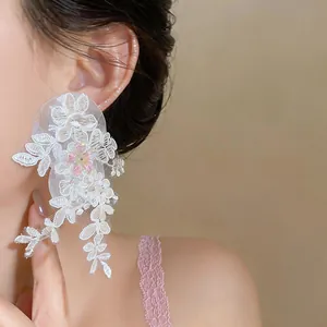 Detailed view of elegant French style white lace flower tassel earrings worn by a model