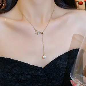 Elegant gold butterfly necklace with sparkling cubic zirconia and pearl drop on model.