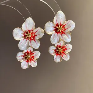 Elegant retro white flower drop earrings with red center detailing and gold-tone finish.