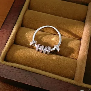Exquisite silver-colored band ring with rotatable pink zircon beads in a velvet box.