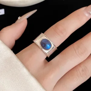 Vue détaillée d'une bague argentée ouverte avec une pierre bleue ovale portée sur un doigt