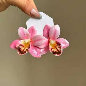 Vue macro de boucles d'oreilles en résine d'orchidée rose brillante sur fond neutre