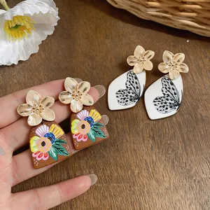 Primo piano di orecchini eleganti con motivi a fiori e farfalle e perni dorati