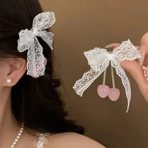 Close-up detail of a sweet white lace bow hair clip featuring pink cherry resin pendants