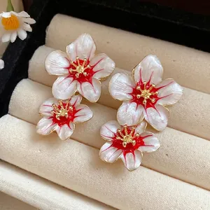 Elegant vintage pearlescent flower stud earrings with red enamel accents and gold hardware.