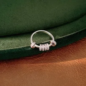 Elegant silver-colored geometric ring with sparkling zircon beads displayed on green velvet