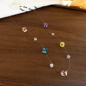 Detailaufnahme von bunten quadratischen Kristallperlen an einer transparenten Kette.